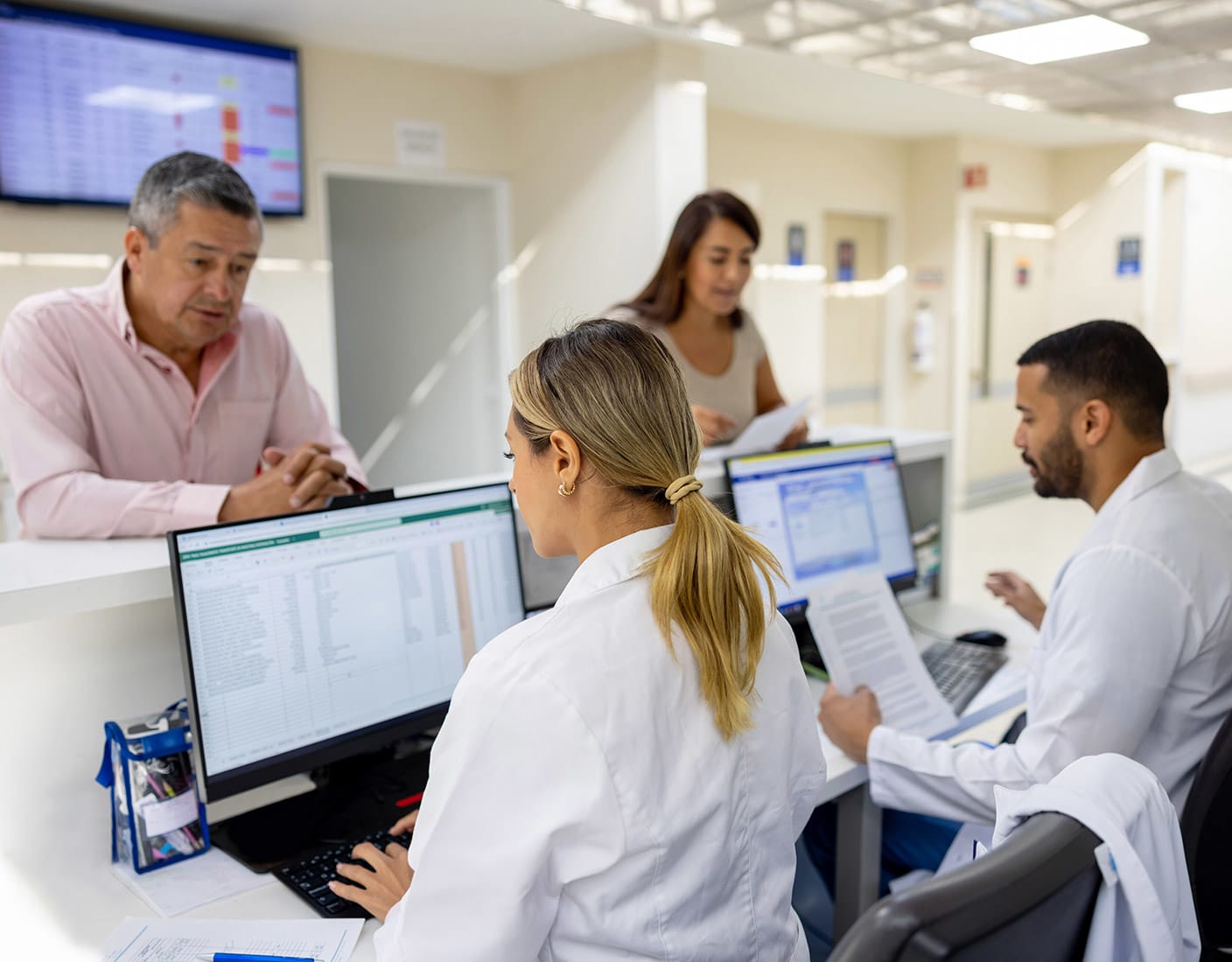 Two individuals asking questions to the hospital staff at the reception desk.
